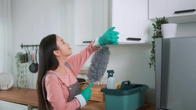 Happy Asian young woman sweeping sofa and furniture to cleaning house, healthy lifestyle concept