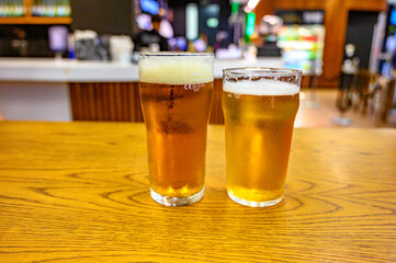 Fresh draught lager or IPA beer is glass served in indoor cafe close up, pint of beer