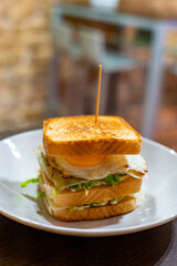 Vegetarian club sandwich with white bread, egg, green lettuce and cheese