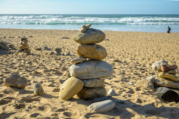 Fototapeta na wymiar Pyramid from stack balanced stones on sandy beach, Atlantic ocean, Portugal