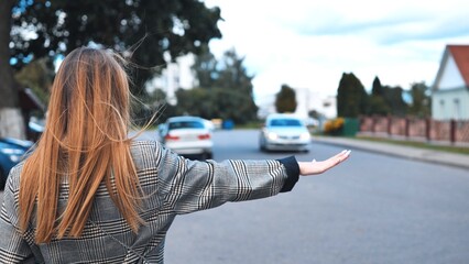 Obraz premium A girl is waving to a cab in the city.