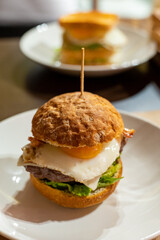 Tasty burger with white crispy ban, beef burger, egg, green lettuce and cheese