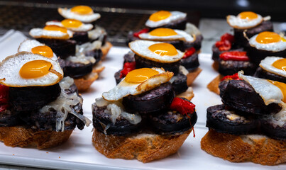 Typical snack of Basque Country, pinchos or pinxtos, small piece of bread with egg, sausage and...