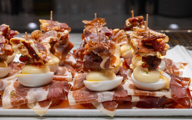 Typical snack of Basque Country, pinchos or pinxtos, small piece of bread on skewers with egg, jamon and different toppings, served in bar in San-Sebastian or Bilbao, Spain