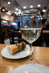 Board with typical snacks of Basque Country, pinchos or pinxtos, skewers or small piece of bread with toppings, served with glass of txakoli wine in bar in San-Sebastian or Bilbao, Spain