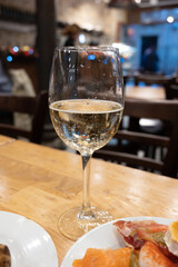 Board with typical snacks of Basque Country, pinchos or pinxtos, skewers or small piece of bread with toppings, served with glass of txakoli wine in bar in San-Sebastian or Bilbao, Spain