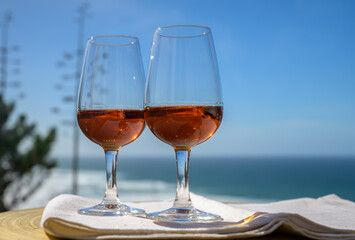 Tasting of sweet moscatel de setubal or porto portuguese wine and view on blue Atlantic ocean near Sintra in Lisbon area, Portugal