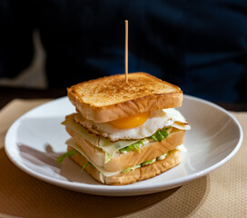 Vegetarian club sandwich with white bread, egg, green lettuce and cheese