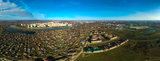 aerial view - low-rise country suburbs of the city of Krasnodar near the bend of the Kuban river with several high-rise buildings and a lake on a sunny winter day - obrazy, fototapety, plakaty