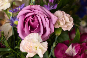 Purple rose in a bouquet of pink and purple flowers.