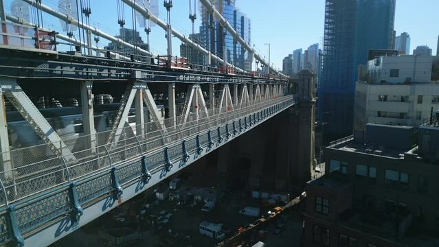 Cars and subway train passing on double deck Manhattan Bridge. Aerial descending footage of transportation in city. New York City, USA