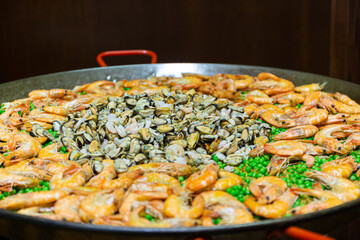 large paella pan with peas and seafood on the stove