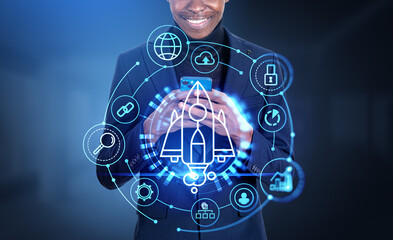 African businessman using smartphone, startup rocket hologram with icons