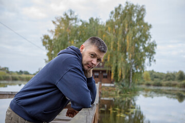 athletic man standing on city bridge over river and looking at camera.
