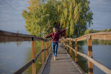 Tourist woman walk by long wooden suspension bridge above river