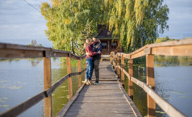 Happy young couple in love walking in bridge at sunset. Man embracing and going to kiss sensual woman.