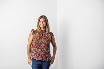 a beautiful caucasian woman in her forties in a casual floral top and denim jeans standing against...
