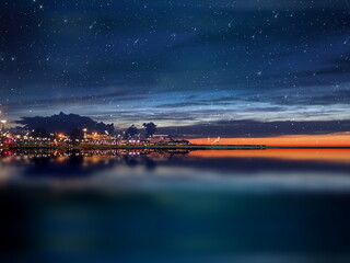  night sea water blurred city light,blue water wave  reflection  starry sky and moon in Italy  port...