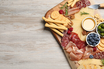 Tasty parmesan cheese and other different appetizers on white wooden table, top view. Space for text