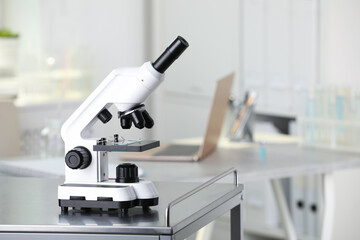 Modern medical microscope on metal table in laboratory. Space for text
