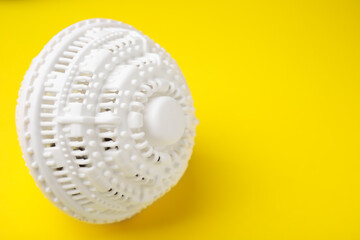 Laundry dryer ball on yellow background, space for text
