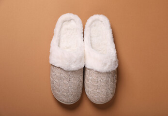 Pair of beautiful soft slippers on light brown background, top view