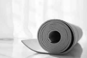 Rolled karemat or fitness mat on floor indoors, closeup. Space for text