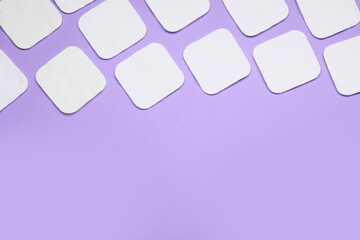 Many cotton pads on lilac background, flat lay. Space for text