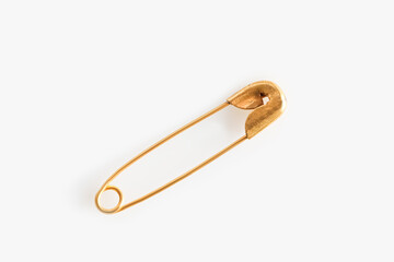 Golden safety pin on white background, top view