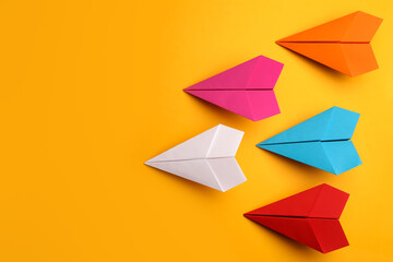 Handmade colorful paper planes on yellow background, flat lay. Space for text