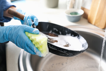 Obraz na płótnie Canvas Woman washing dirty frying pan in sink indoors, closeup