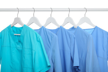 Turquoise and light blue medical uniforms on rack against white background