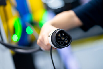 Front view, female hand holding pump, cable, plug, electric car charger, EV car with modern technology, UI, cable, sustainable choice, eco energy