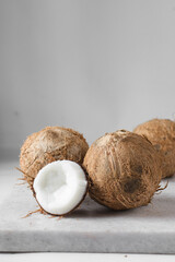 Coconuts on a white chopping board, Cracked coconut next to whole coconut