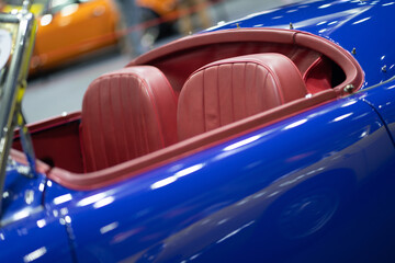 Red interior seat of blue vintage sports car under lighting - Powered by Adobe