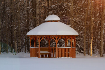 Wooden arbour in the winter forest in snow and warm light.