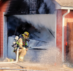 Firefighter uses a hose to battle a house fire