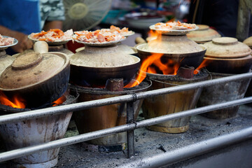 Clay pots cooked on fire charcoal buckets in Kuala Lumpur Chinatown street                             