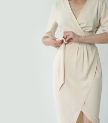 Studio shot of woman in classy simple beige viscose summer dress.	