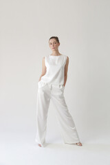 Serie of studio photos of young female model in all white silk outfit, sleeveless blouse and wide...