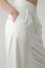 Studio shot of female model wearing white silk trousers.	