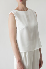 Serie of studio photos of young female model in all white silk outfit, sleeveless blouse and wide...