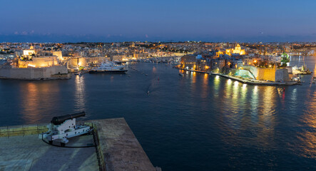 Fototapeta premium Valletta, Malta waterfront at night with a cannon from the Saluting Battery in foreground