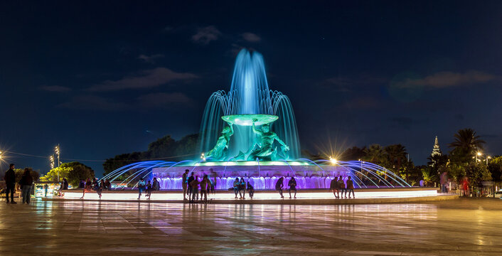 Triton Fountain in Valletta Malta at night with people in silhouette