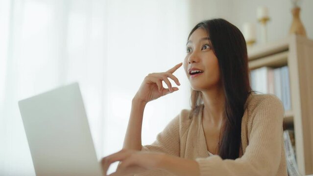 Young asian woman working on computer laptop on desk in living room at home