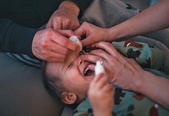 Father dripping eye medicine in the little boy eyes