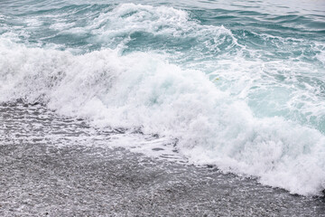 Fototapeta na wymiar foamy coastal sea wave of a pebble beach