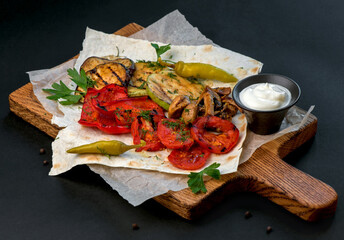 Fried vegetables on a cutting board on a dark wooden background