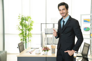 Portrait of businessman doing happy thumbs up gesture with hand to cheer up, business success...