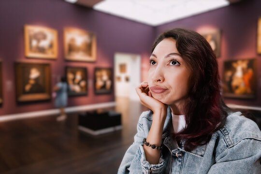 a bored girl visitor or student in an art gallery or museum looks at the masterpieces of classical artists